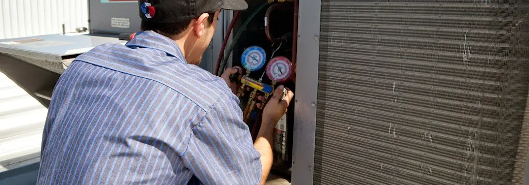 HVAC technician servicing a condenser unit in Summit