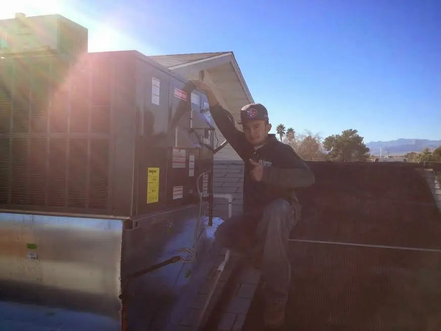 HVAC technician performing Air Duct Cleaning on a rooftop unit in Summit